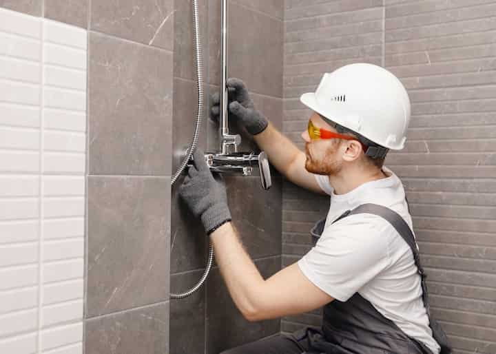 Bathroom Remodeling expert with white and black overalls working on a shower in Bradenton, FL.
